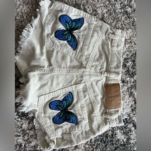 Cream PacSun Jean shorts, with an embroidered butterfly.